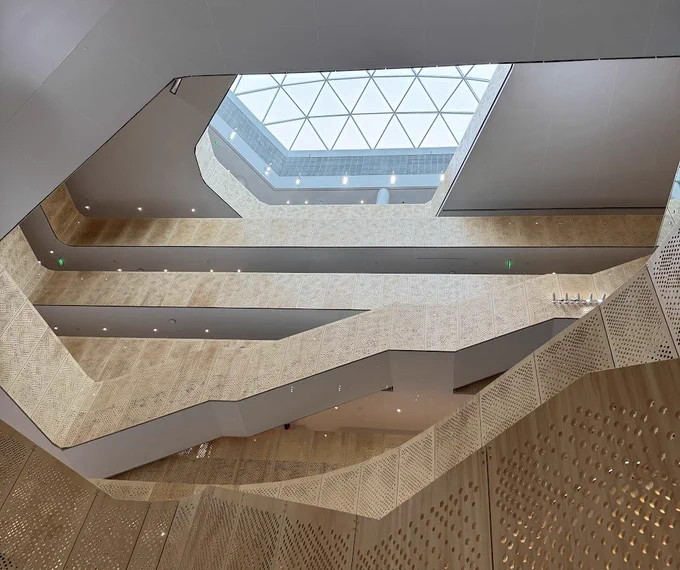 An shot from below of winding wooden staircases and a glass atrium rooftop. The new School of Computer, Data & Information Sciences building at Wisconsin Madison. 