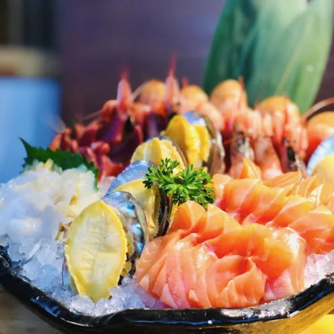 Close-up of a delicious sashimi platter featuring salmon and shrimp, served on ice with garnishes.