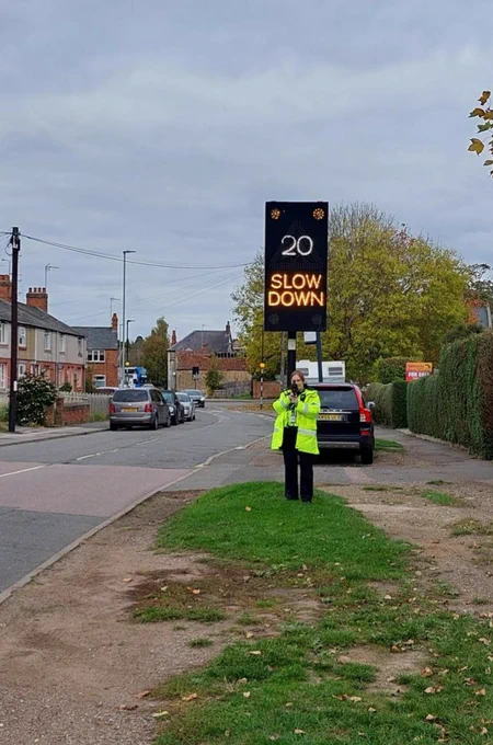 Officer holds speed gun on Vernon Road in Towcester, in front of a VAS sign