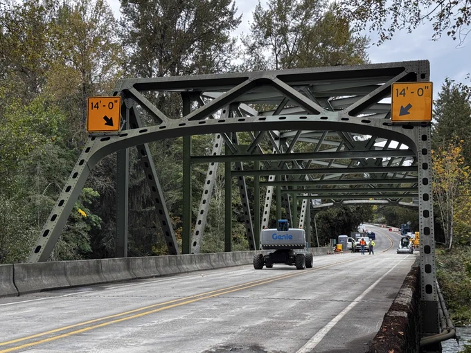 A steel bridge painted green with two 14-foot clearance signs on either side