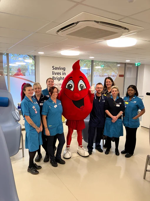 A group photo of the NHS Blood and Transplant Brighton team wearing their uniforms with Billy Blood Drop mascot.
