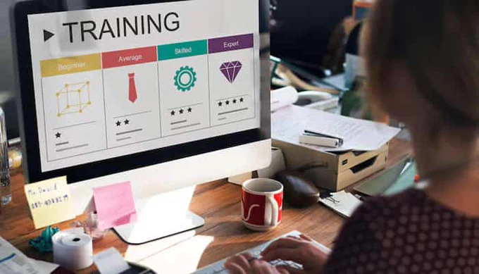 A professional working on a computer displaying a training progress screen with skill levels from beginner to expert, representing the growth and development focus of a Training Business.
