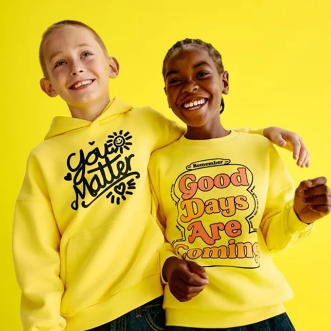 two children in yellow slogan sweatshirts printed 'You matter' and Good days are coming'
