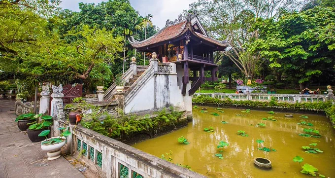 An image of the "one pillar pagoda" in Hanoi, Vietnam. A pagoda sits atop a pillar in a rectangular pond with lily pads and green water. A staircase runs from the edge of the pond up to the pagoda.