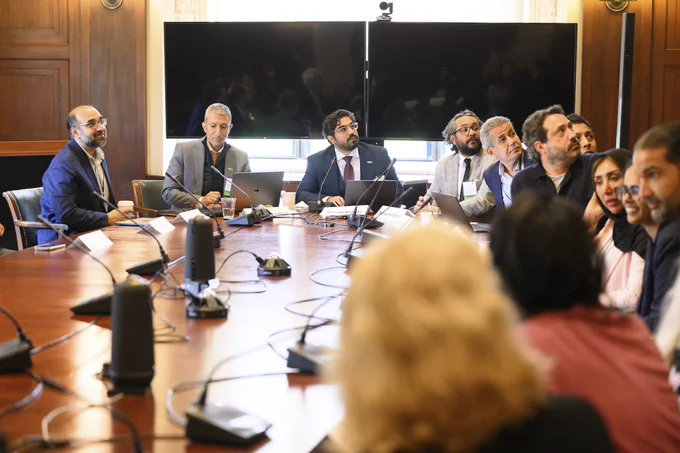 Attendees in a discussion around a large conference room table.