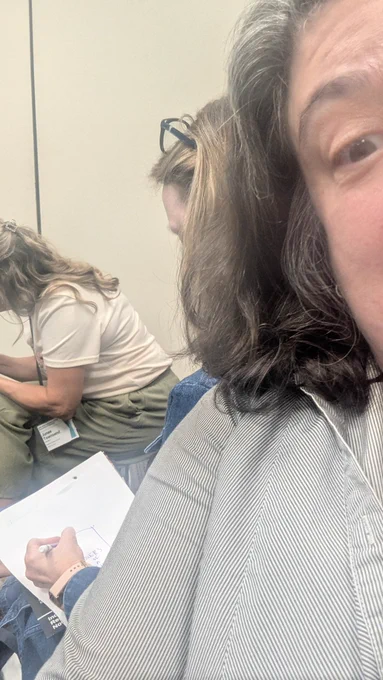 Someone taking a selfie with someone behind them drawing a picture 