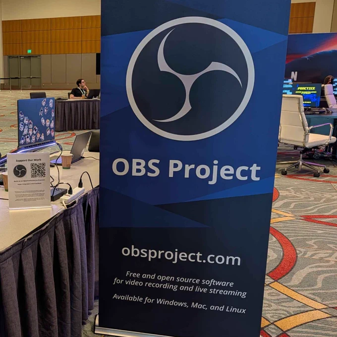 A photo of a stand up banner in a convention hall ballroom featuring the OBS Project logo, name and tagline.