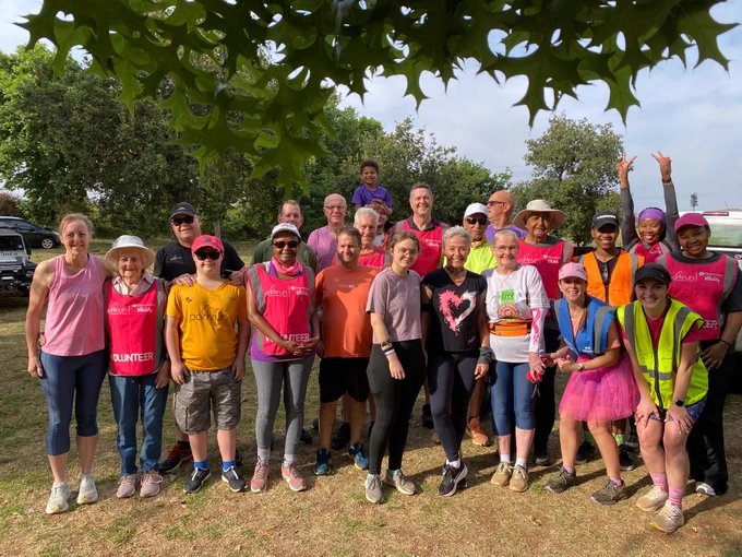 A group of parkrunners smiling for a photo, some wearing tutus.