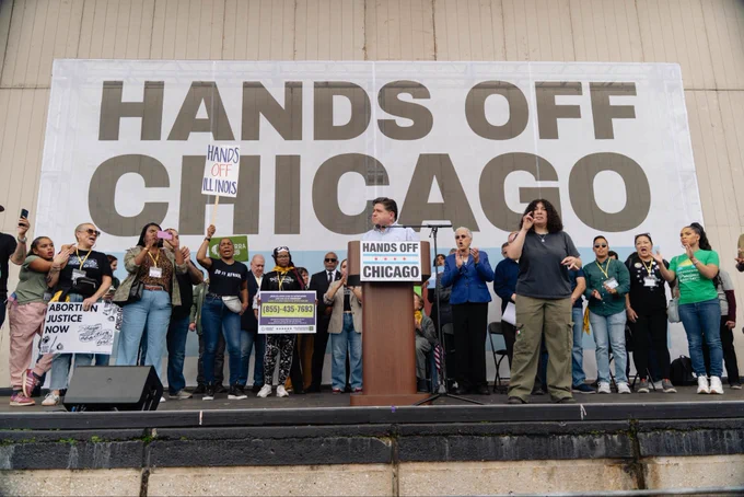 Governor Pritzker stands at a podium in front of several elected officials across Illinois.