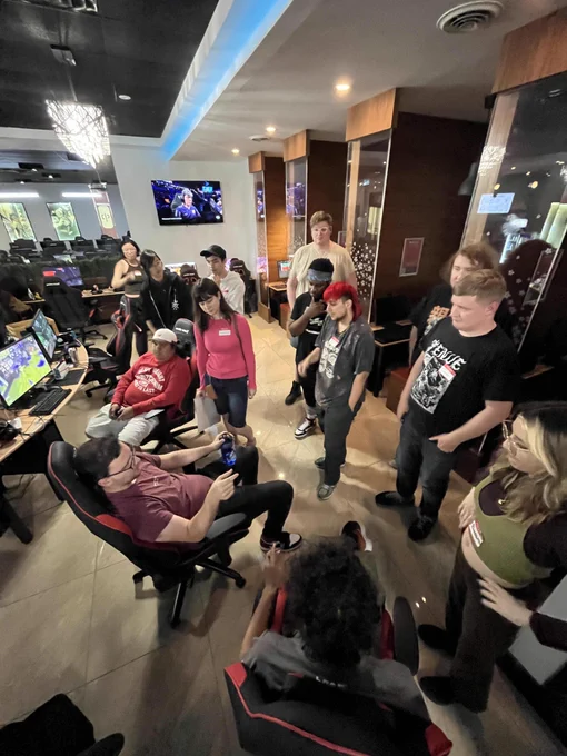 Wide angle from  above of various Squid Social attendees facing each other in a slight circle, a few are stiting.