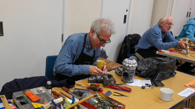 Two men work in a repair cafe fixing household items