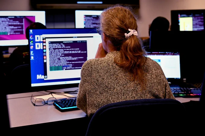 A woman sits at a computer in a classroom.
