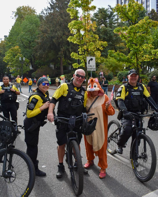 People peacefully marching during the second No Kings protest on Saturday, Oct. 18, 2025. Portland Police taking a photo with a protestor wearing an animal costume