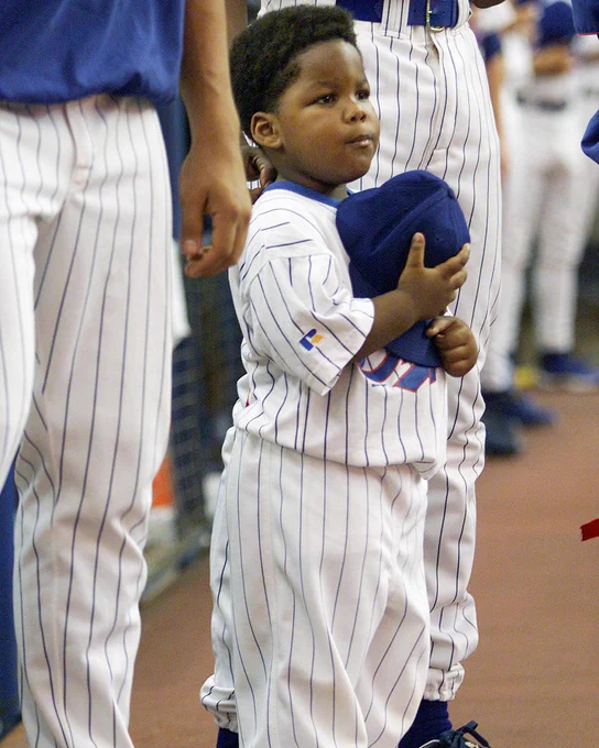 A photo of a young Vladimir Guerrero Jr. in a home white Montreal Expos uniform. He holds his hat over his heart.