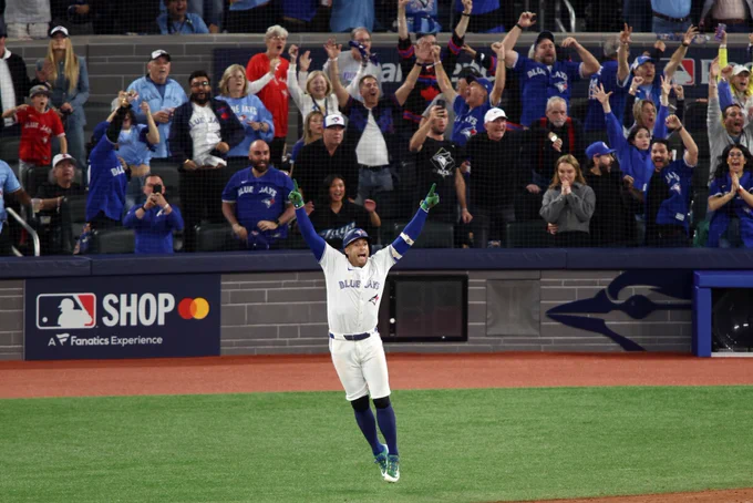 George Springer jumps in the air with his arms out after hitting a go-ahead home run. The crowd goes wild in the background.
