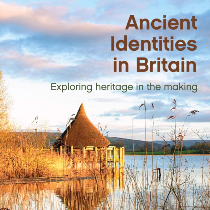 Cover of 'Ancient Identities in Britain' featuring a thatched roof building by a serene lake surrounded by reeds, under a sunset sky.