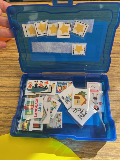 blue plastic box open. velcro holds the tokens under the lid and preferred item cards are laminated and loose on the bottom part.