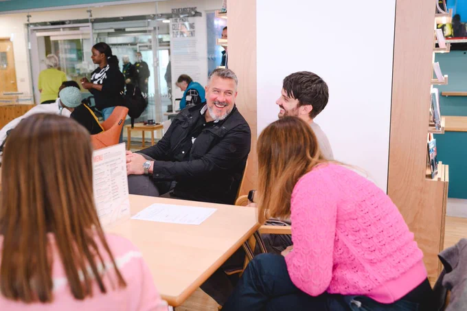 Group of people seated around a table in a casual setting, engaged in conversation.