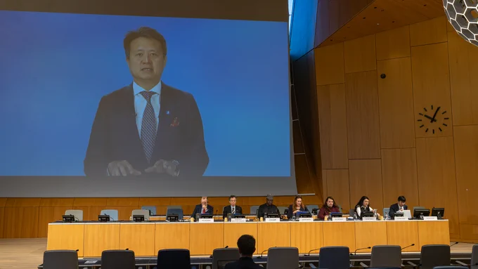A large screen projection of a WIPO Director General Daren Tang addressing the audience remotely at the 12th WIPO Conversation on Intellectual Property and Frontier Technologies, while panelists sit in the WIPO conference room.