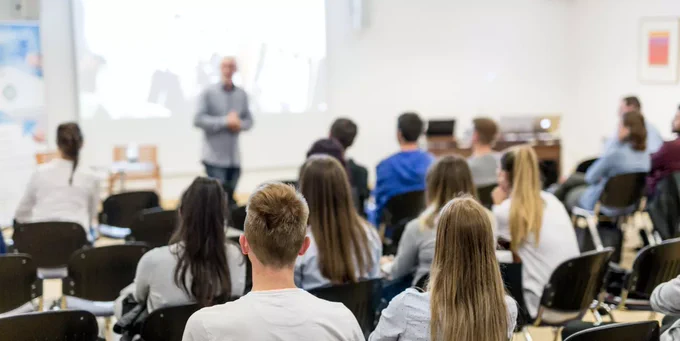A professor speaks at the front of a classroom.