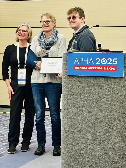A group of people stand and smile with an award