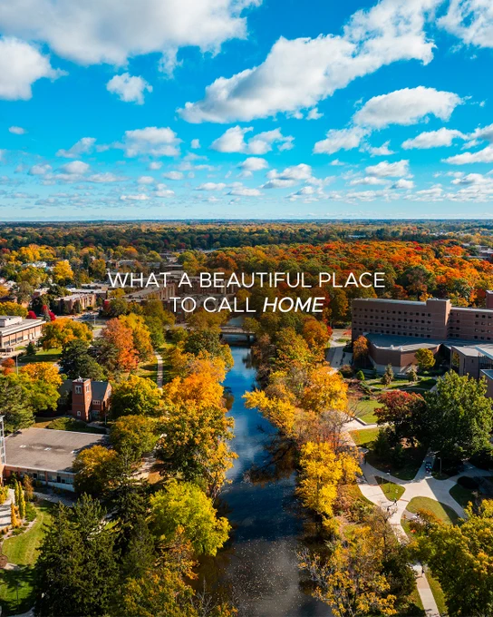 Aerial view of the Red Cedar River running through MSU's campus surrounded by trees in autumn colors, under a blue sky with clouds. The text overlay reads, "WHAT A BEAUTIFUL PLACE TO CALL HOME."