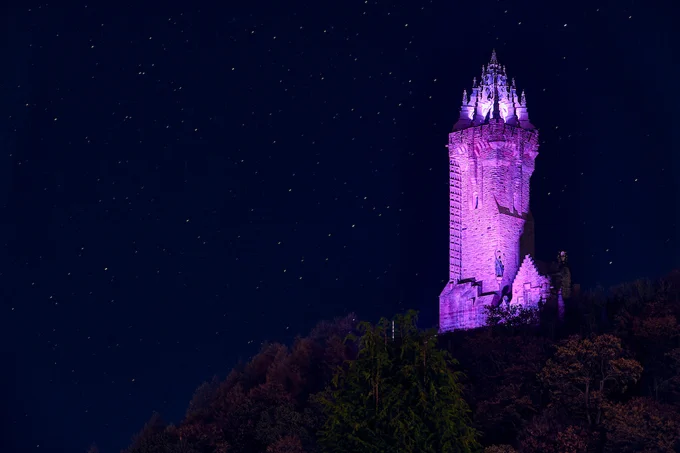  67m 19th century tower, known as the Wallace Monument, illuminated in purple for World Stroke Day, against a starry, black sky.   