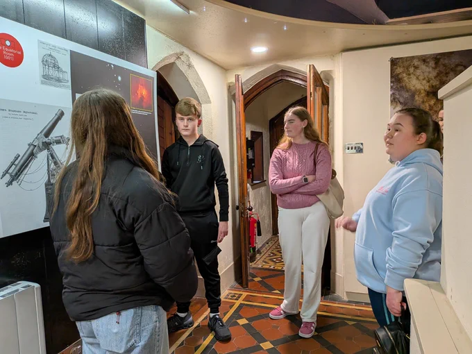 Photo of Patrick, Emma and Ava,students with low vision getting a tour of UCCs observatory from Ava of the Visitors Service