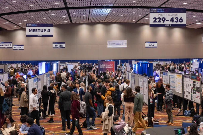 Large, busy exhibit hall filled with attendees viewing scientific posters and engaging in discussions during the 2025 ASBMB Annual Meeting in Chicago.