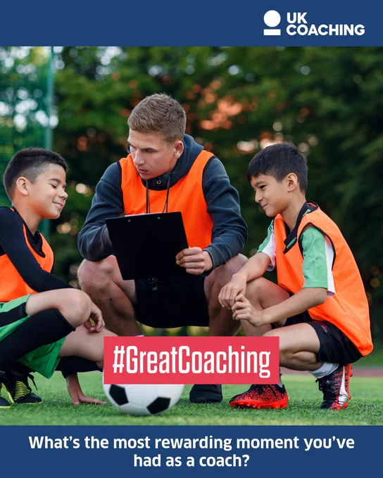 A coach wearing a UK Coaching vest is kneeling with a clipboard, discussing strategy with two young football players on a grassy field. The players, wearing bibs and engaged in the conversation, are sitting beside a football. The image includes the hashtag #GreatCoaching and poses the question, "What's the most rewarding moment you've had as a coach?"