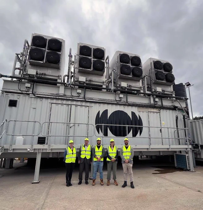 A group of people standing in front of a direct air capture unit.