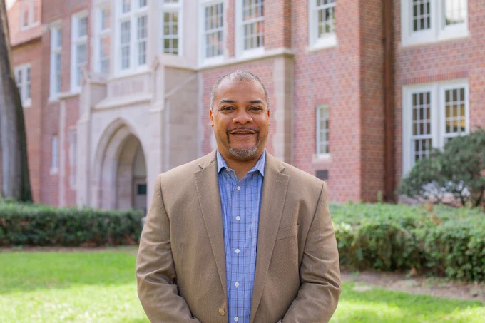 Headshot of Rob Moore, Ph.D., standing outside Norman Hall at the University of Florida. He is smiling in a sports coat on a sunny, bright day.