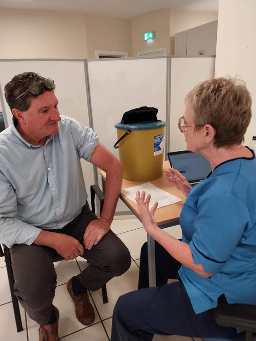 A man talking to a nurse about getting a flu jab