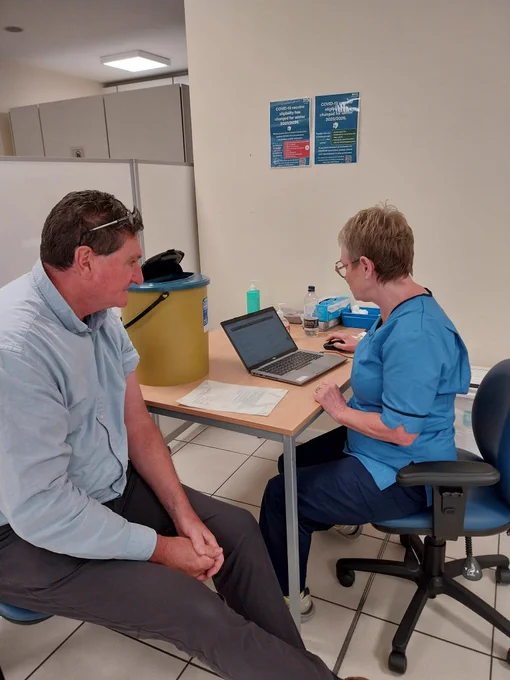 A man talking to a nurse about getting a flu jab