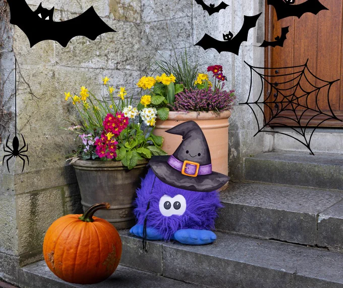 Professor Fluffy on the steps on UCC's Quad wearing a witches hat, surrounded by Halloween decorations 
