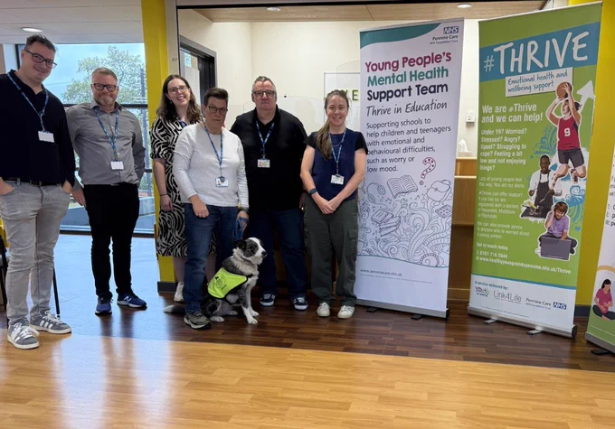Six people and a dog at the clinic where #Thrive is based, next to banners for mental health services