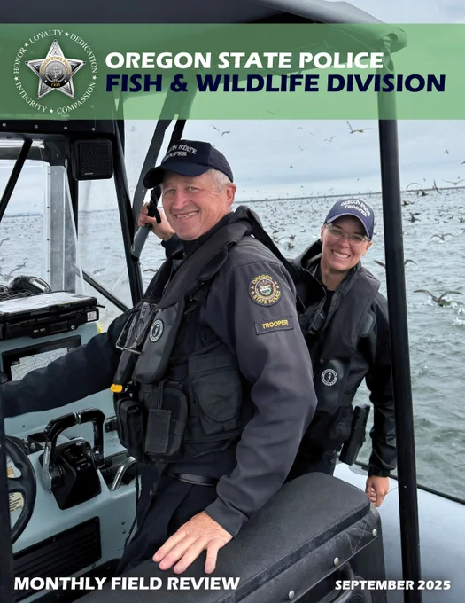 Two Oregon State Police Fish and Wildlife Troopers smiling while standing on a boat in the Columbia River.