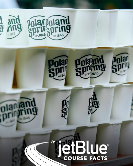 Photo of Poland Spring water cups stacked on top of each other with the “jetBlue COURSE FACTS” badge overlayed at the bottom center