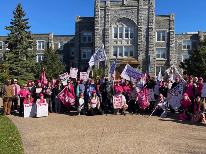 A large group photo of a rally in front of a University.