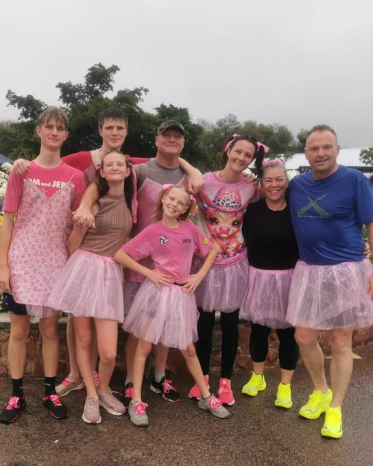  A big family all dressed in pink tutus smiling for a photo.