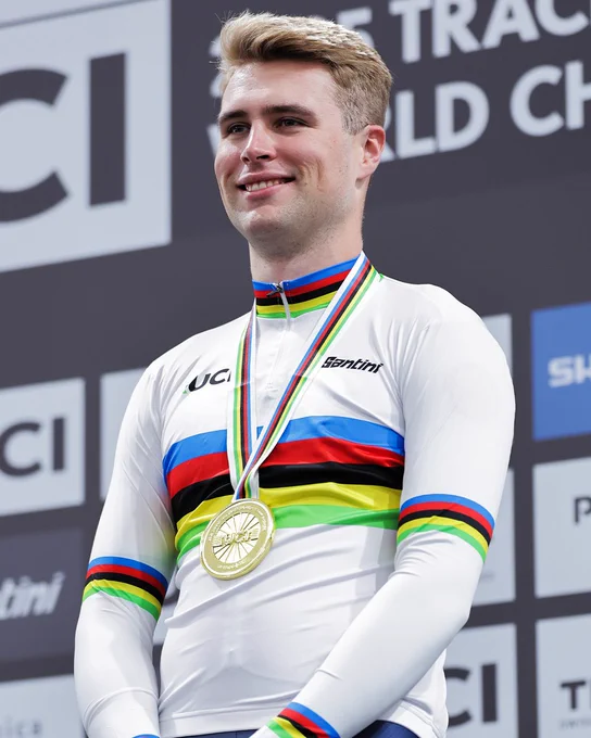 Josh Charlton stands on the podium in his rainbow jerseys with his gold medal round his neck