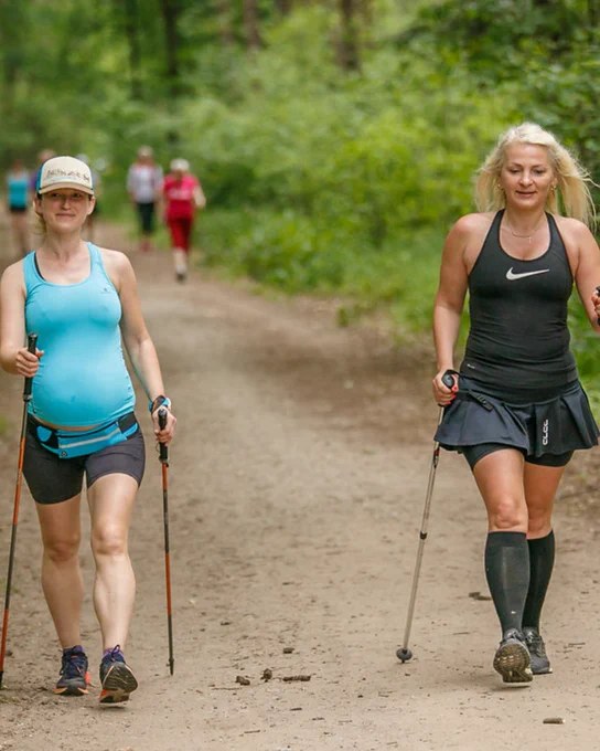 Two parkwalkers walking with poles on a track.