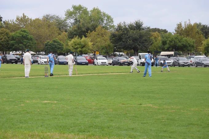 View from the boundary shows players in blue and batters in white