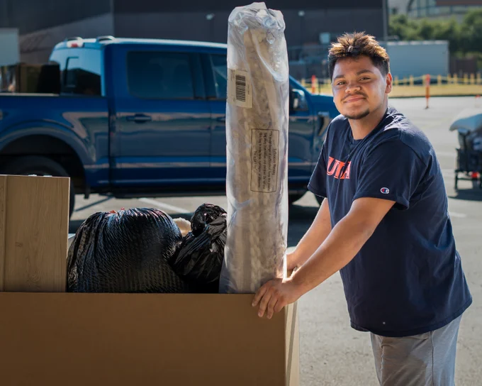 A student is moving a cart full of household items on Move-in day.