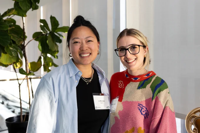 Two young women stand together smiling at the camera