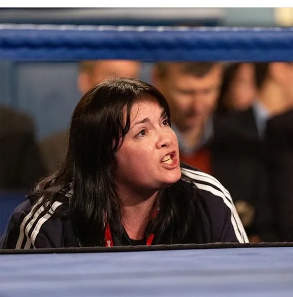 Suzanne giving animated instructions from the sidelines of a boxing ring.