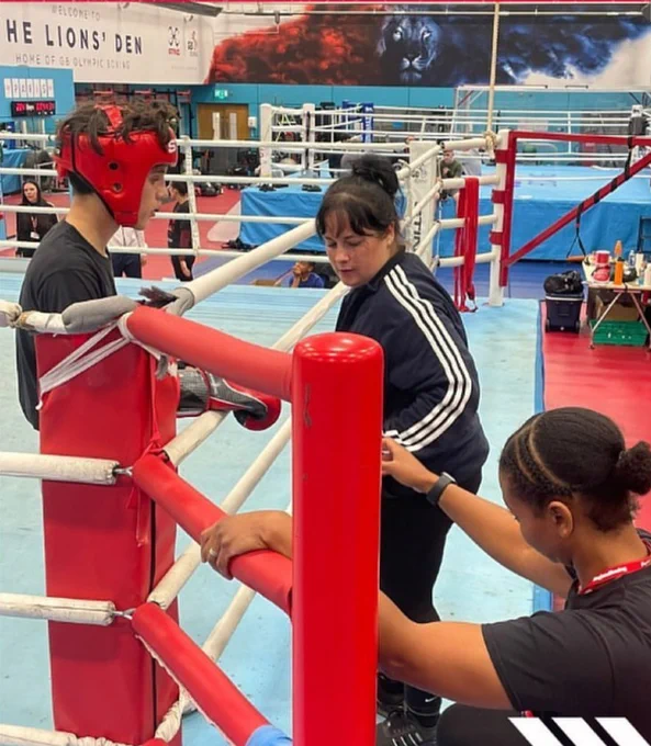 Suzanne assists a boxer while another individual stands in the background.