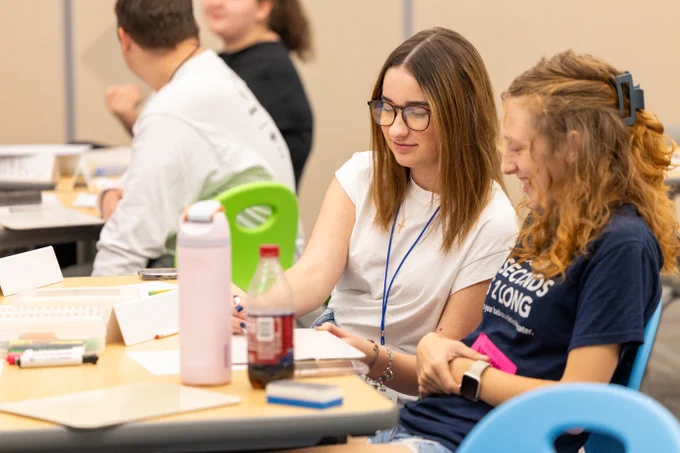 Participants engaging in a classroom setting with various study materials on the desks, including notebooks and beverages.