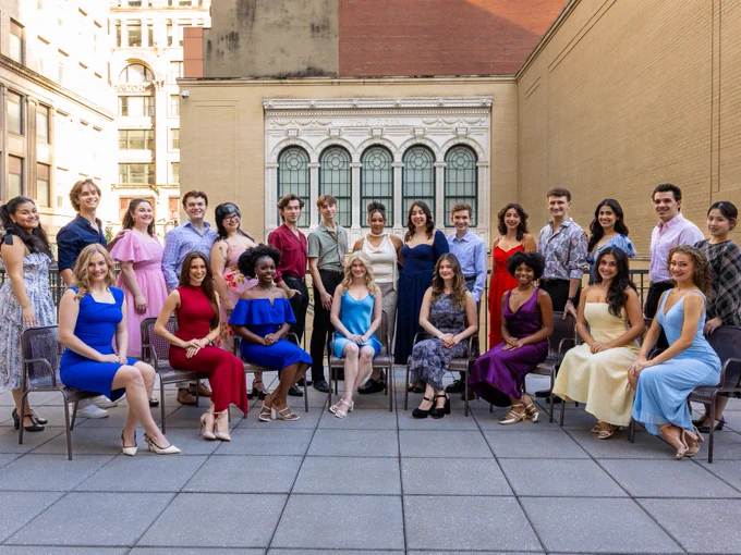 Group of twenty-four students posing for a photo at the Pittsburgh Playhouse. Some are standing while others are seated in chairs, dressed in semi-formal attire.