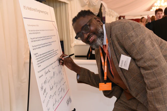 A professional signing their name on a 'National Engineering Day' pledge board at the Engineers 2030 launch parliamentary event.